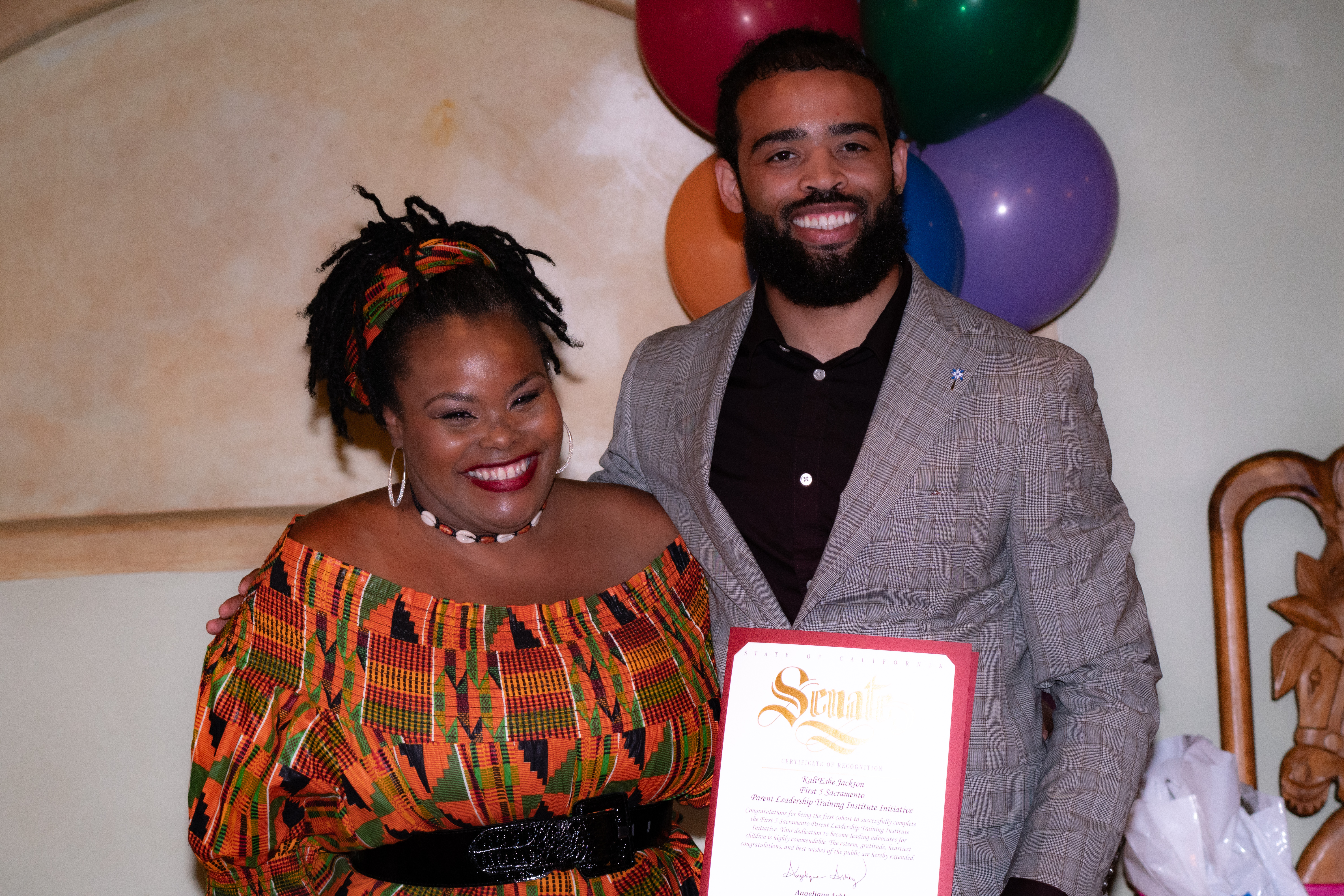 PLTI Parent graduate, Kali'Eshe Jackson receives a certificate of recognition from Elijah Orr, representing Senator Ashby's office